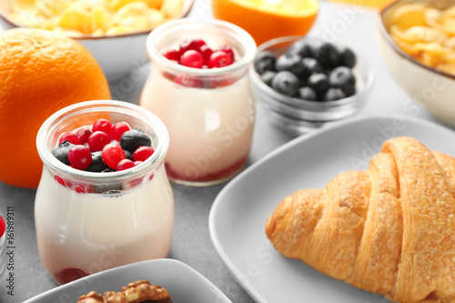 Jar with yogurt and served breakfast on table