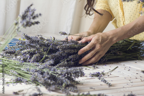 Florist at work: woman creating bouquet of natural lavender flowers, in te wooden table, small business concept