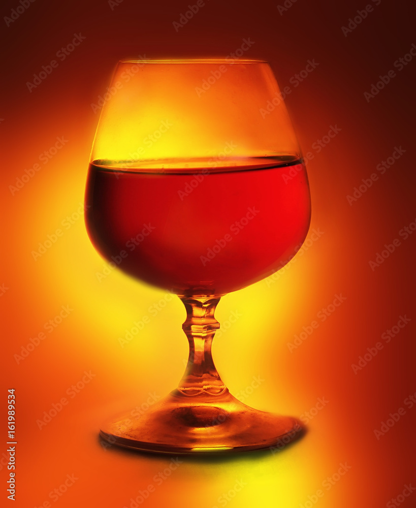 A glass of brandy on an orange background