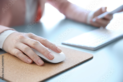 Female hand holding computer mouse on pad © Africa Studio