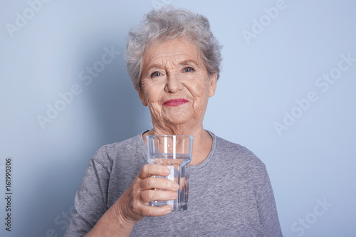 Elderly woman holding glass...