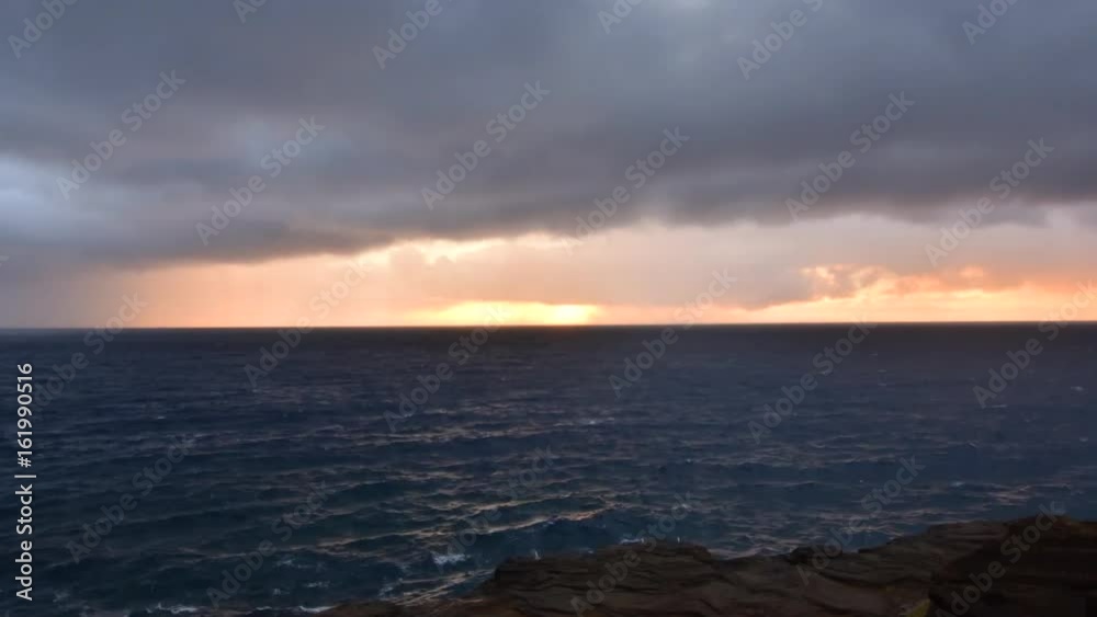 Time lapse sunrise through rain clouds over ocean in Oahu Time lapse sunrise through rain clouds over ocean in Oahu