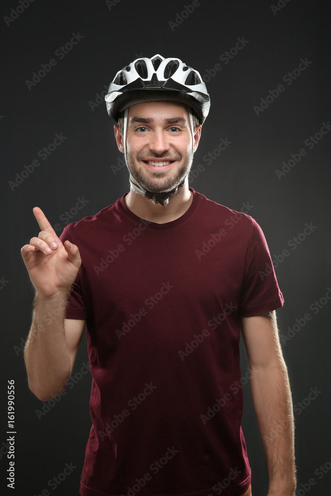 Handsome young bicycle rider with helmet on dark background Handsome young bicycle rider with helmet on dark background