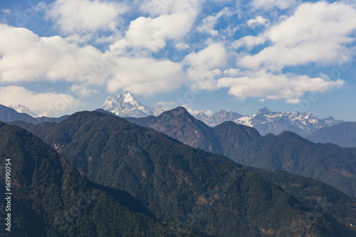 Kangchenjunga mountain with clouds above. Among green hills that view in the evening in North Sikkim, India.