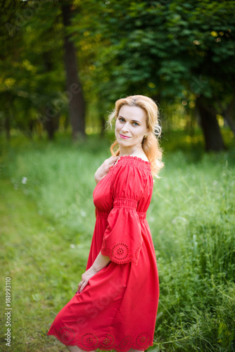 Fashion pretty happy smiling woman in red dress in park