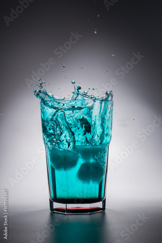 Glass of green water with splash and ice