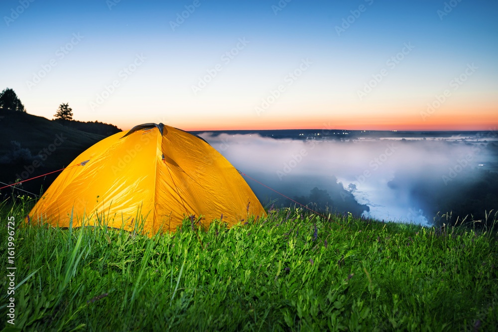 Illuminated from within an orange tent on hil