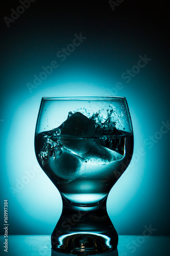 Glass of water with ice on gradient background