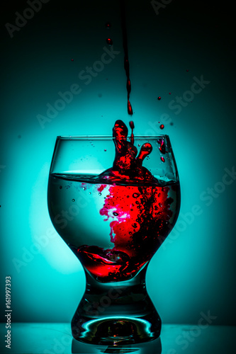 Glass of water with splash red dye