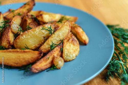 Roasted potatoes with salt pepper and cumin on wooden background