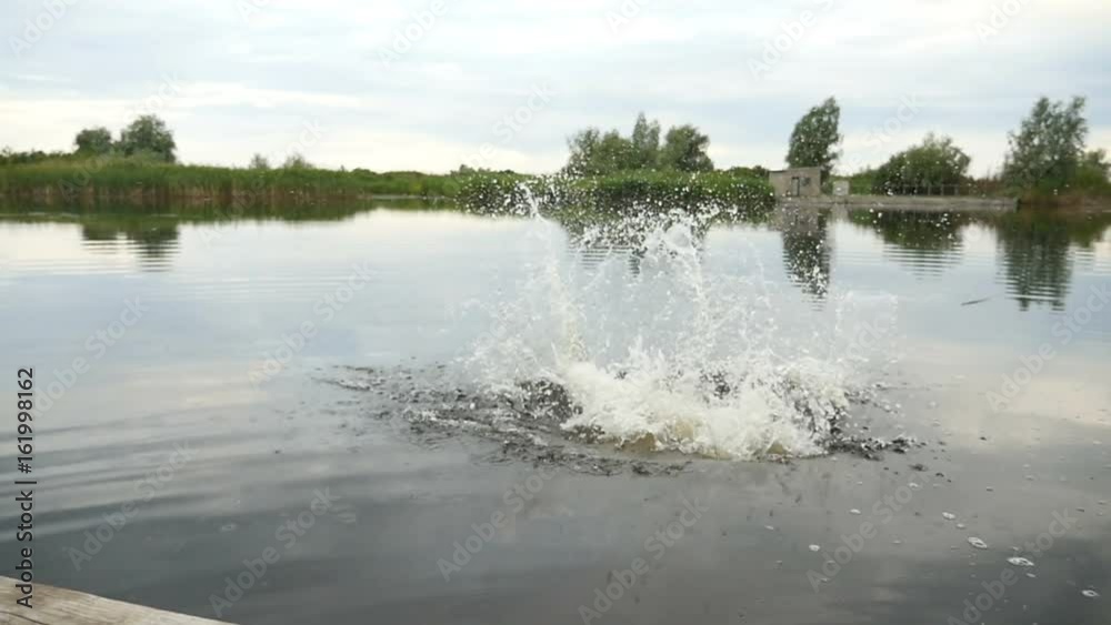 Impressive view on a young boywho jumps in lake waters from a wooden bridge in a sunny day in summer in slow motion. Impressive view on a young boywho jumps in lake waters from a wooden bridge in a sunny day in summer in slow motion.
