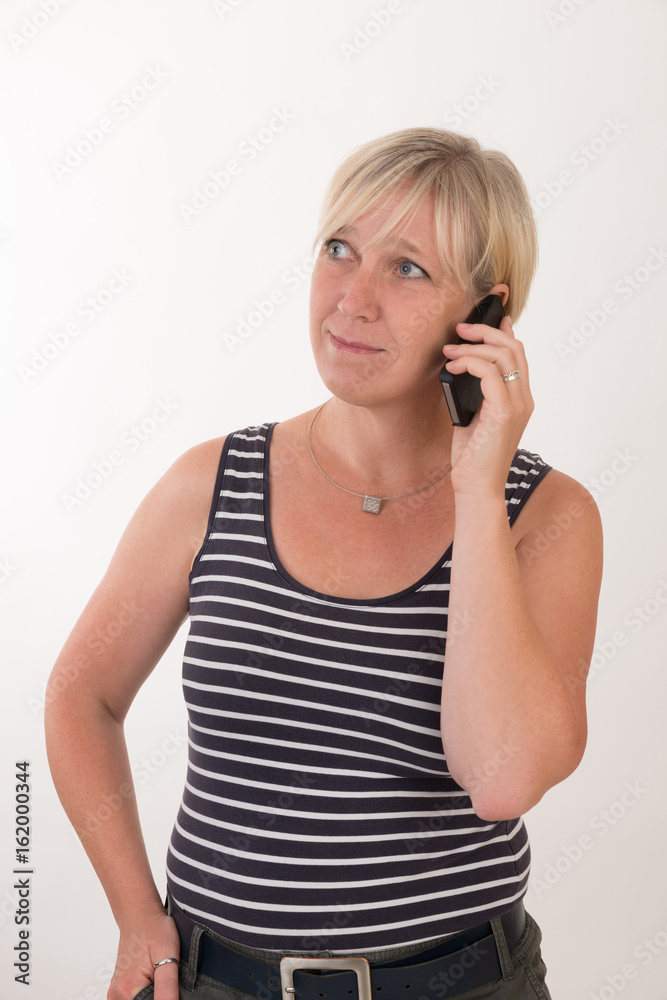 portrait of a attractive blond haired mid aged european woman wearing blue striped top acting with cellular phone - studio shot on white background. portrait of a attractive blond haired mid aged european woman wearing blue striped top acting with cellular phone - studio shot on white background.