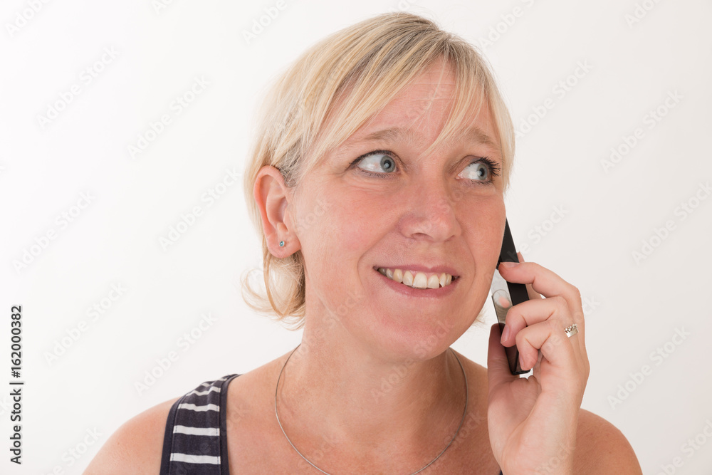 portrait of a attractive blond haired mid aged european woman wearing blue striped top acting with cellular phone - studio shot on white background. portrait of a attractive blond haired mid aged european woman wearing blue striped top acting with cellular phone - studio shot on white background.