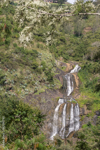 Nilgiri Hills, India - October 26, 2013: White water of Kattipatti Waterfalls in Masamigulli Forest tumbles over gray and beige rocks, framed by the green of the jungle. photo