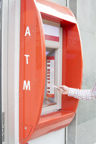Hand of a man with a credit card, using an ATM. Man using an atm machine with his credit card.