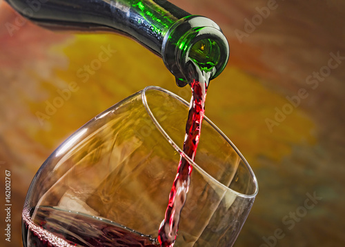 Wine pours into the glass of the bottle