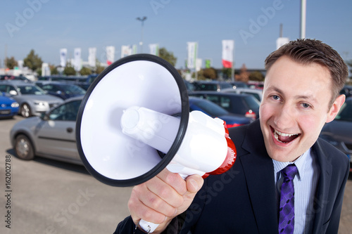 Autoverkäufer mit Megafon lacht Porträt photo