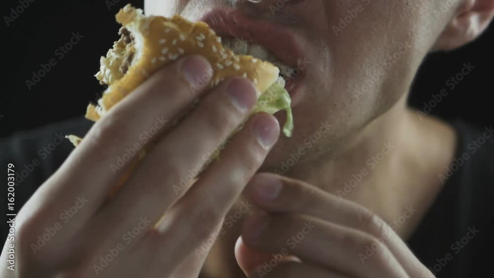 Close up Man eats a hamburger in slow motion Close up Man eats a hamburger in slow motion