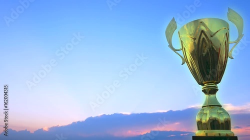 Bright golden winner cup on the blue sky background for sport competitions photo