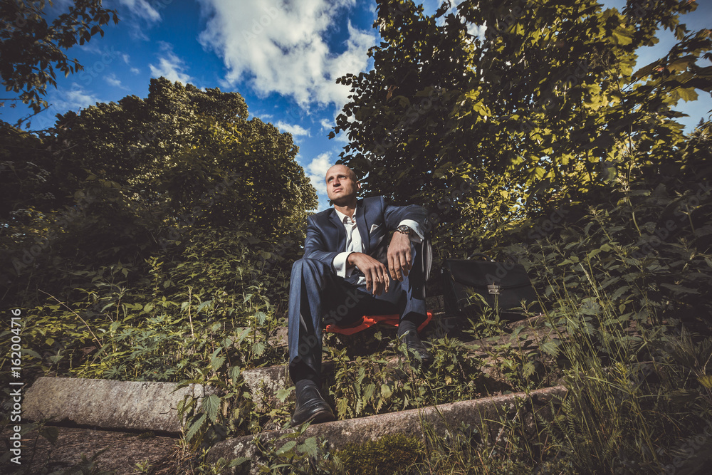Serious man sitting on a old broken stairs Serious man sitting on a old broken stairs