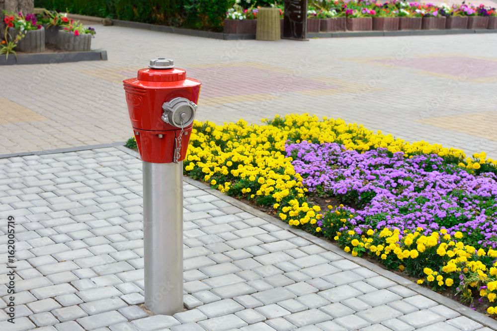 Red fire hydrant on metal resistance on the pavement in the city. Red fire hydrant on metal resistance on the pavement in the city.