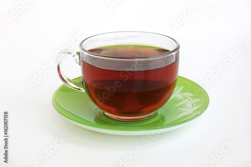 glass Cup with tea on a green saucer on a white background