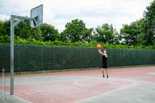 Teenage boy shooting a basketball on a court © Ben Gingell