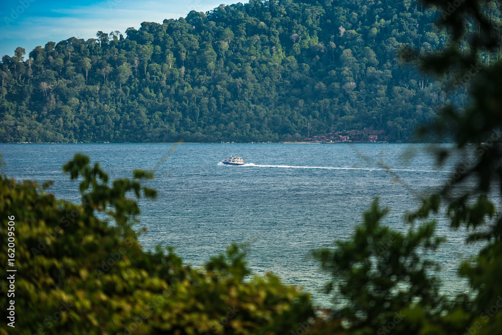 Boat crosses big bay of a tropical island in the middle of the malaysian jungle Boat crosses big bay of a tropical island in the middle of the malaysian jungle
