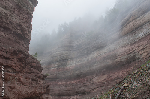 Red sandstones covered by fog in Bletterbach canyon, Dolomites, Italy