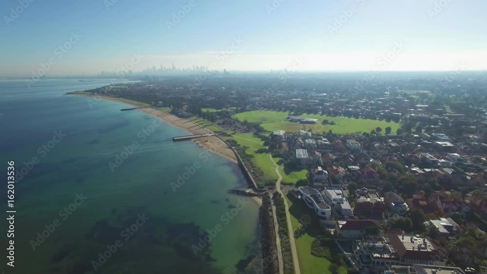 Slow aerial descend above Melbourne coastline with CBD skyscrapers in the distance on bright sunny day Slow aerial descend above Melbourne coastline with CBD skyscrapers in the distance on bright sunny day