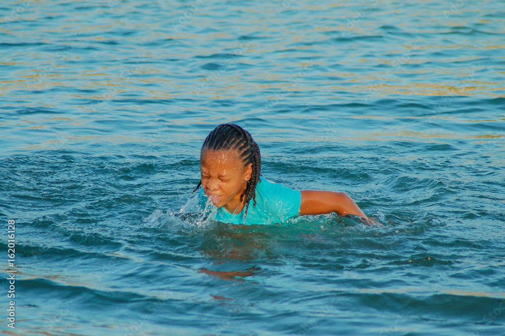 Young girl coming from under the water swimming