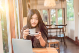 asian woman drinking coffee and looking something on laptop in the conner in  coffee shop