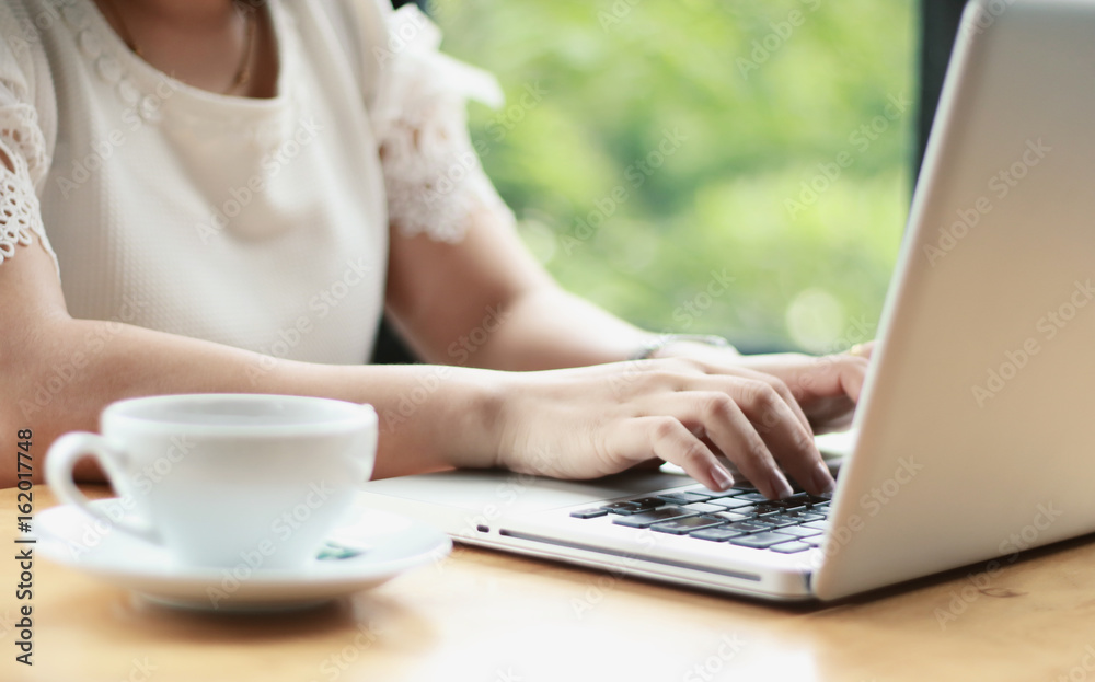 Concentrated at work. Confident young woman in smart casual wear working on laptop while sitting near window in creative office or cafe Concentrated at work. Confident young woman in smart casual wear working on laptop while sitting near window in creative office or cafe