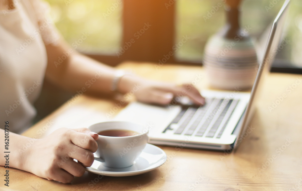 Fototapeta premium Concentrated at work. Confident young woman in smart casual wear working on laptop while sitting near window in creative office or cafe
