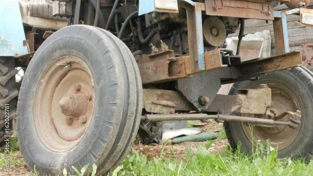 An old rusty tractor stands near the field. The machine for agriculture is waiting for the processing of the field