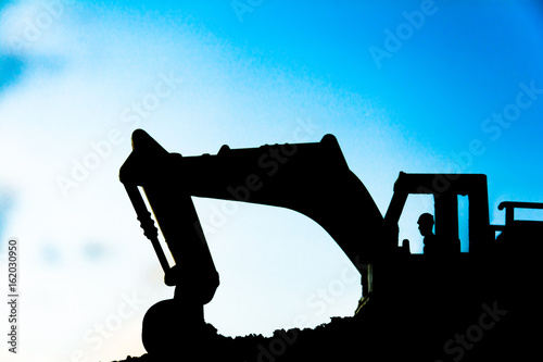silhouette tracked excavator Sand and stone And sky background