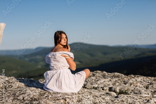 Wallpaper Mural Beautiful girl remains on top of a mountain and looks at the horizon with a beautiful background. A colorful photo of a natural sunset, a miracle, incredible, a dance, hair in the wind Torontodigital.ca