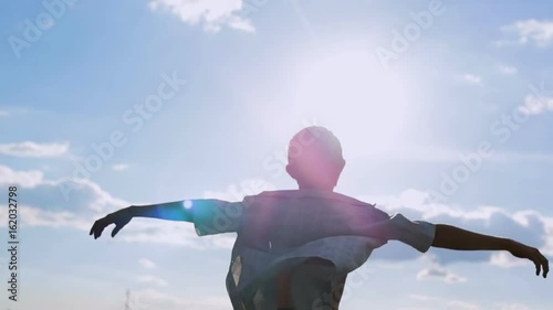 A carefree and free boy raised his hands and looked at the sky