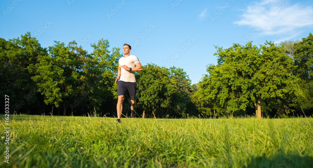 A handsome young man running during sunset in a park A handsome young man running during sunset in a park