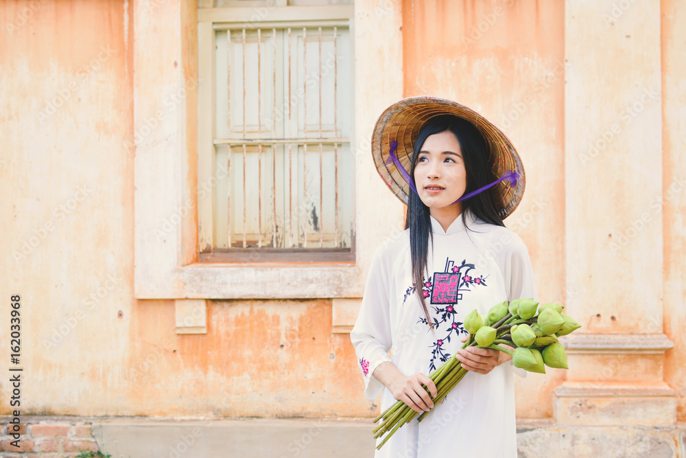 Beautiful women Vietnam with white ao dai dress in old city , selective and soft focus of face color vintage style