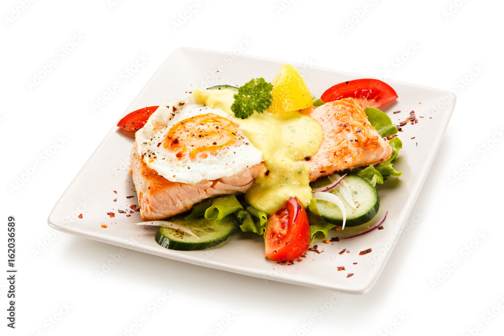 Grilled salmon with fried egg and vegetables on white background Grilled salmon with fried egg and vegetables on white background