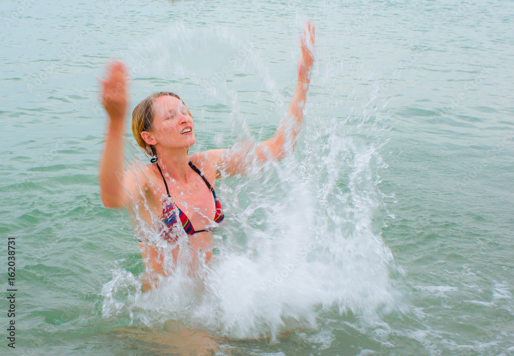 Happiness Attractive girl in the sea splashing water on beach