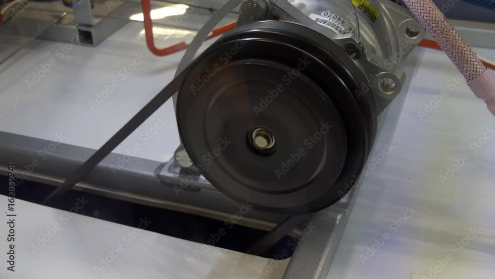 Close up of working electric motor with pulley and belt on it spinning