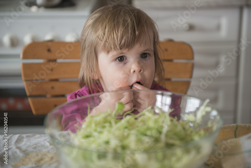 Little girl putting cabbage salad in mouth