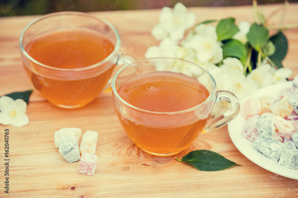 Two cups of green tea with jasmine decorated with a turkish delight on wooden table Two cups of green tea with jasmine decorated with a turkish delight on wooden table