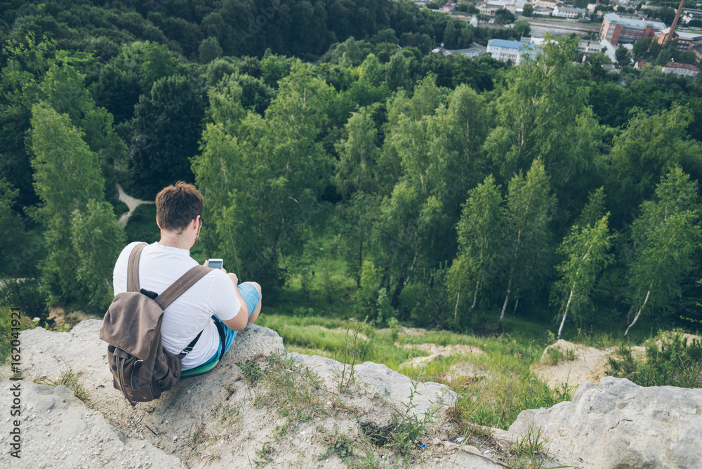 Fototapeta premium man sits on the peak and texting