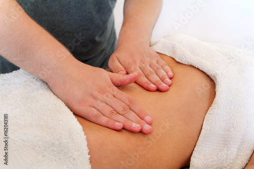 Belly massage in massage studio. Close up of hands massaging female abdomen. Masseur massaging girls belly. Therapist applying pressure on belly. In spa center. Body and health care, medicine concept.