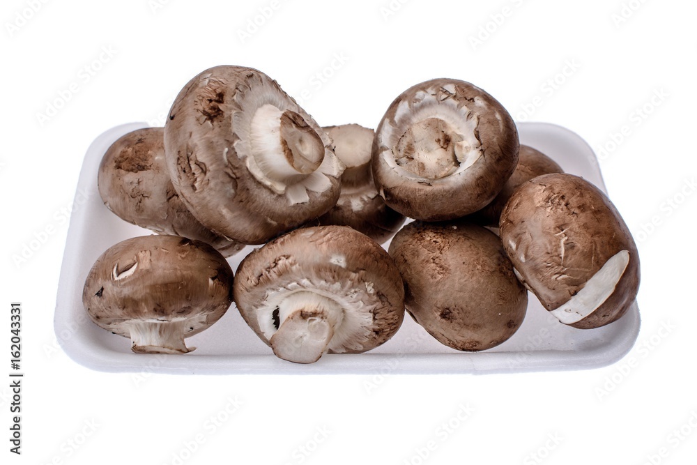 Mushrooms champignons lie on a white tray, isolated on a white background Mushrooms champignons lie on a white tray, isolated on a white background