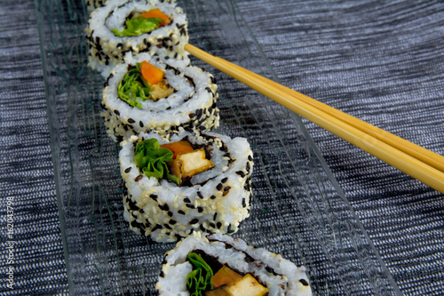 Vegan sushi on glass plate with chopsticks photo