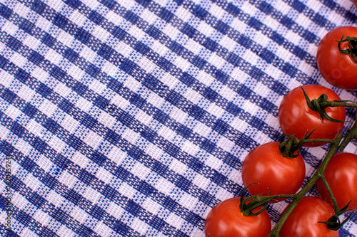 Red cherry tomatoes lie on a blue towel, place for text, background